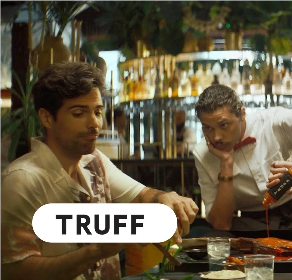 A restaurant patron and a waiter who's pouring Truff hot sauce, with the Truff logo overlaid.